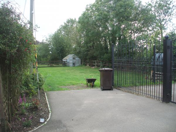 From the house with hideous gates to right. Busy A road to right of boundary